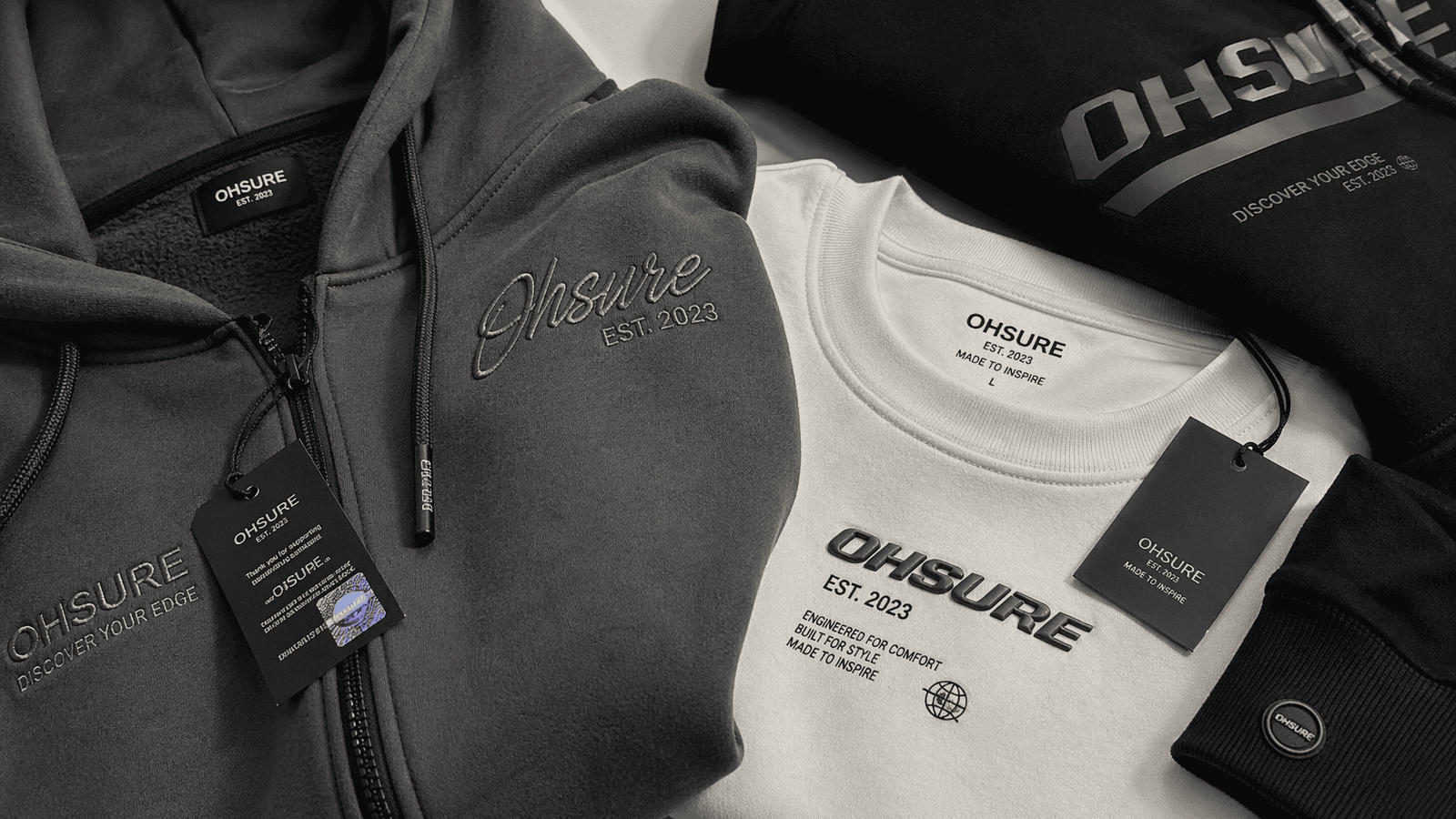 Close-up of streetwear hoodie showing embroidery, puff print and screen printing details, fabric texture visible, labels and trims on table, soft studio lighting, ultra realistic --ar 16:9 --style raw --v 6